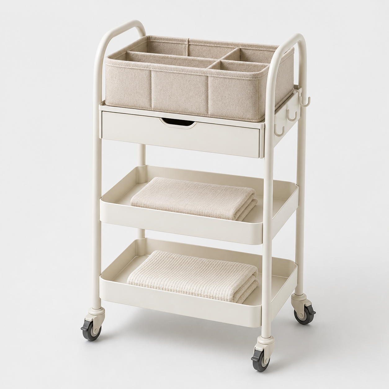 Unbranded cream three-tier rolling nursery cart with felt diaper caddy, drawer, hooks, and lockable wheels